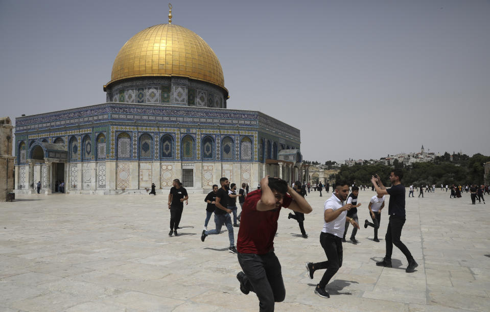Palestinians run from sound bombs thrown by Israeli police in front of the Dome of the Rock shrine at al-Aqsa mosque complex in Jerusalem, Friday, May 21, 202, as aa cease-fire took effect between Hamas and Israel after 11-day war. (AP Photo/Mahmoud Illean)