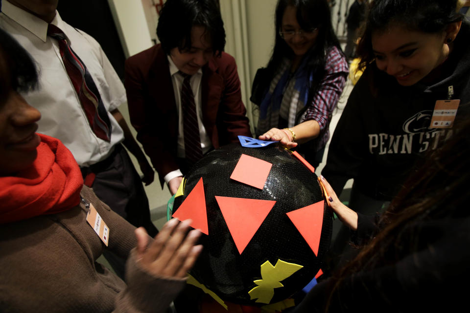 Students visiting the new National Museum of Mathematics put shapes on a three-dimensional surface in New York, Monday, Dec. 17, 2012. The museum is aimed at kids aged 8 to 13, and curators have given the place a playground feel. The 40 exhibits include a "wall of fire" made up of laser lights that teaches kids about geometry and a square-wheeled tricycle that still manages to produce a smooth ride thanks to a wavy track. (AP Photo/Seth Wenig)