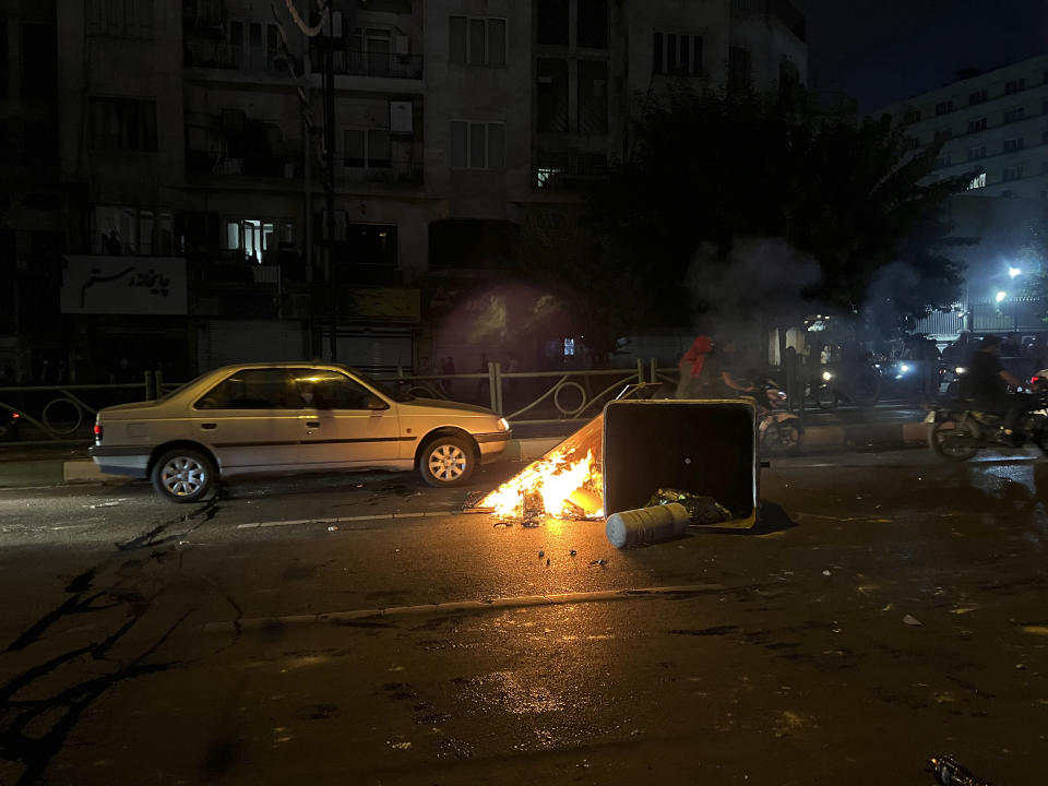 In this Tuesday, Sept. 20, 2022, photo taken by an individual not employed by the Associated Press and obtained by the AP outside Iran, stuff is set on fire by protesters during a protest over the death of a young woman who had been detained for violating the country's conservative dress code, in downtown Tehran, Iran. Iran faced international criticism on Tuesday over the death of a woman held by its morality police, which ignited three days of protests, including clashes with security forces in the capital and other unrest that claimed at least three lives. (AP Photo)