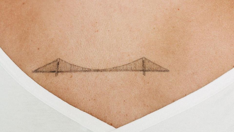 woman with back tattoo of bridge