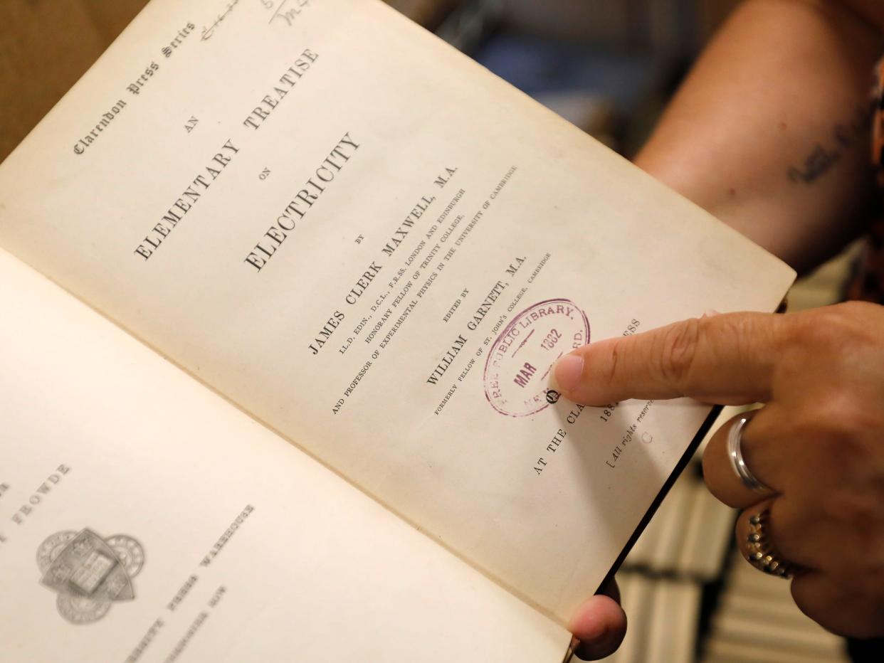 New Bedford Public Library Director Olivia Melo, points to a stamp dating to 1882 when the New Bedford library system acquired the book, on Friday, July 7, 2023, in New Bedford, Massachusetts.