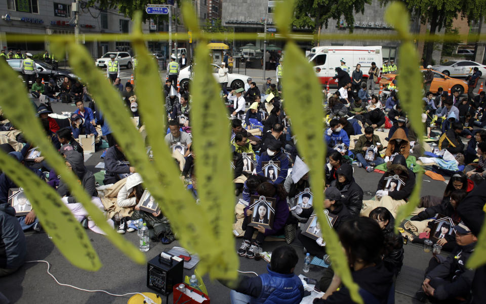 Family members holding the portraits of the victims of the sunken ferry Sewol, sit on a street near the presidential Blue House in Seoul, South Korea, Friday, May 9, 2014. Family members marched to the presidential Blue House in Seoul early Friday calling for a meeting with President Park Geun-hye but ended up sitting on streets near the presidential palace after police officers blocked them. Park's office said a senior presidential official plans to meet them later Friday. (AP Photo/Lee Jin-man)