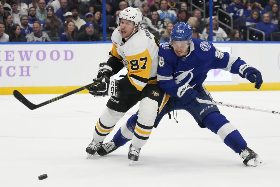 Pittsburgh Penguins center Sidney Crosby (87) beats Tampa Bay Lightning defenseman Mikhail Sergachev (98) to a loose puck during the third period of an NHL hockey game Thursday, Nov. 30, 2023, in Tampa, Fla. (AP Photo/Chris O'Meara)