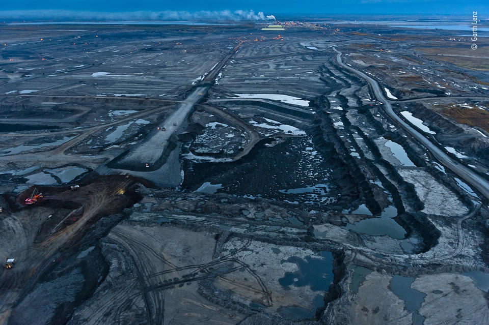 As twilight falls on the Alberta tar sands, the stripped landscape takes on an oily blue tint.