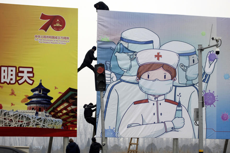 Workers put up government propaganda to fight against the viral outbreak in Beijing, China on Thursday, Feb. 20, 2020. A viral outbreak that began in China has infected more than 75,000 people globally. The World Health Organization has named the illness COVID-19, referring to its origin late last year and the coronavirus that causes it. (AP Photo/Ng Han Guan)