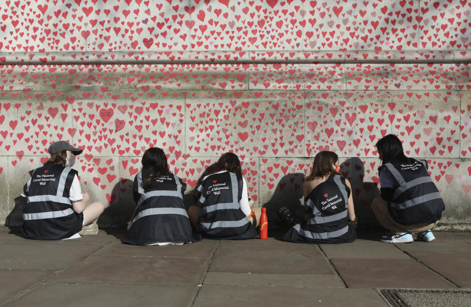 People draw hearts on the National Covid Memorial Wall, which is being painted in memory of the more than 145,000 people who have died in the UK from coronavirus, on the Embankment in central London, Tuesday, March 30, 2021. (Luciana Guerra/PA via AP)