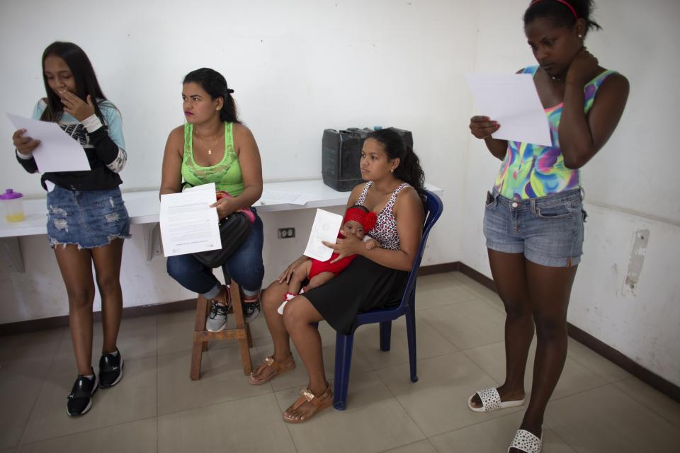 In this photo taken July 25, 2019, Nicol Ramirez, 15, sits with her baby girl and other women with forms to sign that authorizes the administration of hormonal implants to prevent pregnancies, of which there are a very limited number, in the Caucaguita neighborhood on the outskirts of Caracas, Venezuela. With condoms and birth control pills either impossible to find or too expensive, Ramírez found out she was pregnant at 14 with her boyfriend, who responded coldly to her pregnancy and hasn't heard from him since. "The situation in this country isn't one for having children," Ramirez said. "I'm still a girl myself." (AP Photo/Ariana Cubillos)