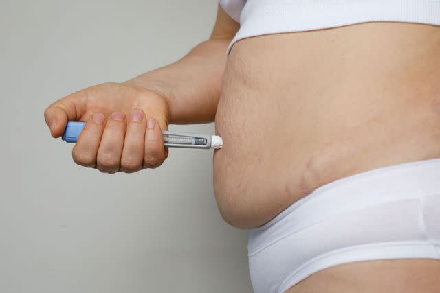 <p>Getty</p> A woman injecting a weight loss pen into her stomach (stock image)