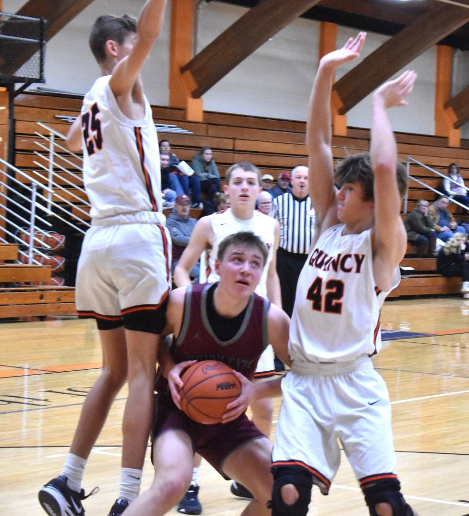 Union City's Aidan Decker goes up strong in the paint while Quincy's Alex Dunn and Brandon Miner (42) defend