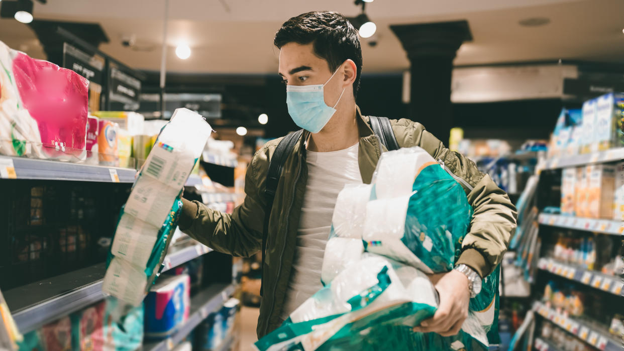 Young Man shopping in a supermarket, breathing through a medical mask because of the danger of getting the flu virus, influenza infection.