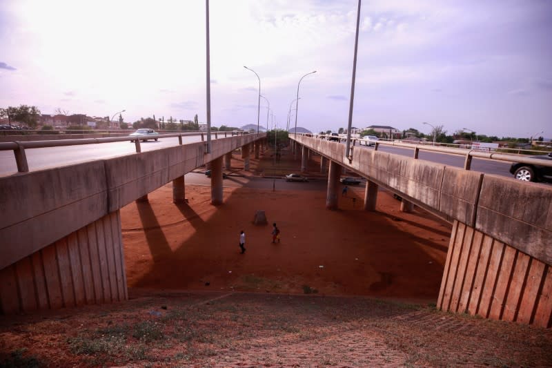 People walk under the bridge, as the spread of the coronavirus disease (COVID-19) continues in Abuja