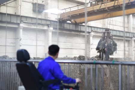 Worker operates a crane lifting garbage for incineration at a waste-to-energy plant in Kaili, Qiandongnan Miao and Dong Autonomous Prefecture, Guizhou