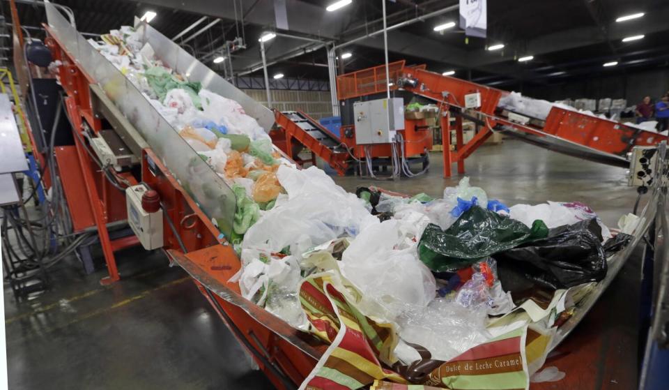 A conveyor at a recycling plant carries mixed plastics into a device that will shred them.