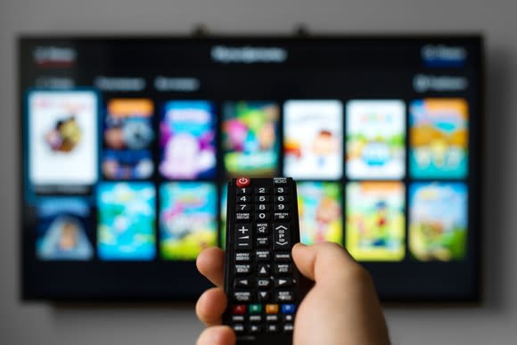 A man pointing a remote at a blurred out television.