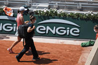 Poland's Iga Swiątek, left, leaves the court with a physiotherapist as she plays Maria Sakkari of Greece during their quarterfinal match of the French Open tennis tournament at the Roland Garros stadium Wednesday, June 9, 2021 in Paris. (AP Photo/Thibault Camus)