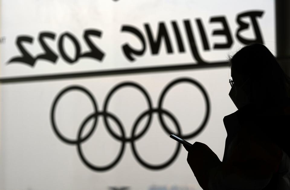 A woman looks at her phone as she passes an Olympic logo inside the main media center for the Beijing Winter Olympics Tuesday, Jan. 18, 2022, in Beijing. (AP Photo/David J. Phillip)