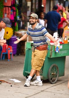 Lin-Manuel Miranda poses in front of a cart that sells flavored ice.