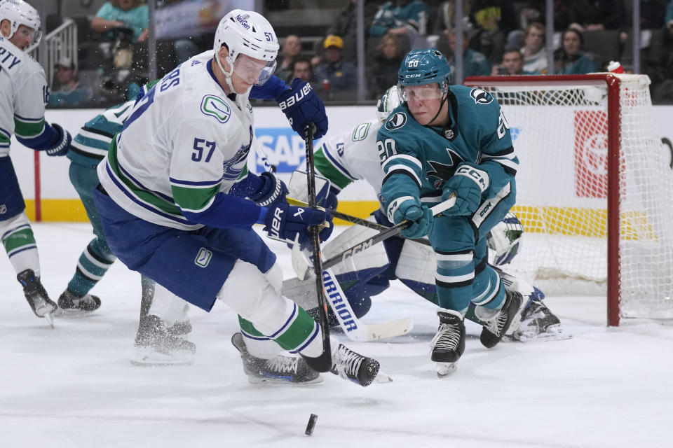 Vancouver Canucks defenseman Tyler Myers (57) skates toward the puck next to San Jose Sharks left wing Fabian Zetterlund during the first period of an NHL hockey game in San Jose, Calif., Saturday, Nov. 25, 2023. (AP Photo/Jeff Chiu)