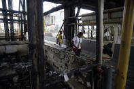 People walk through burnt toll gates with anti police slogans sprayed across, in Lagos Friday, Oct. 23, 2020. Resentment lingered with the smell of charred tires Friday as Nigeria's streets were relatively calm after days of protests over police abuses, while authorities gave little acknowledgement to reports of the military killing at least 12 peaceful demonstrators earlier this week. (AP Photo/Sunday Alamba)