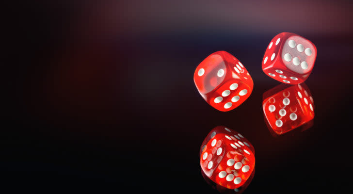 A photo of 2 red dice rolling on a black mirrored background.