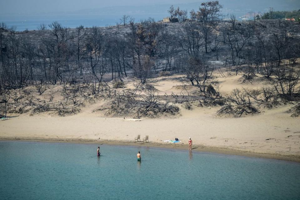 A woman enters the sea from a beach where wildfires destroyed the woods, at Glystra near the village of Gennadi in the southern part of the Greek island of Rhodes, on July 27.<span class="copyright">Angelos Tzortzinis—AFP/Getty Images</span>