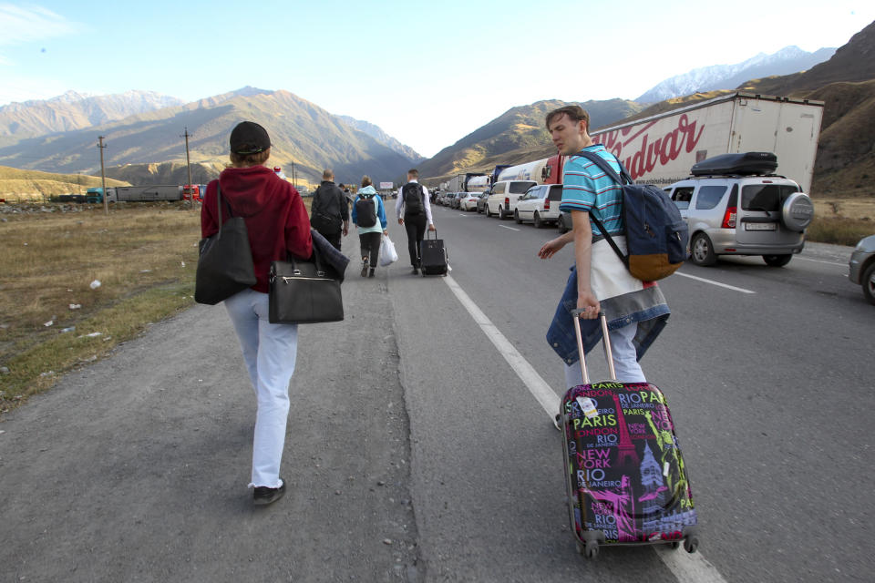 People walk toward the border crossing at Verkhny Lars between Georgia, bottom, and Russia leaving Chmi, North Ossetia–Alania Republic, Russia, Wednesday, Sept. 28, 2022. Long lines of vehicles have formed at a border crossing between Russia's North Ossetia region and Georgia after Moscow announced a partial military mobilization. A day after President Vladimir Putin ordered a partial mobilization to bolster his troops in Ukraine, many Russians are leaving their homes. (AP Photo)