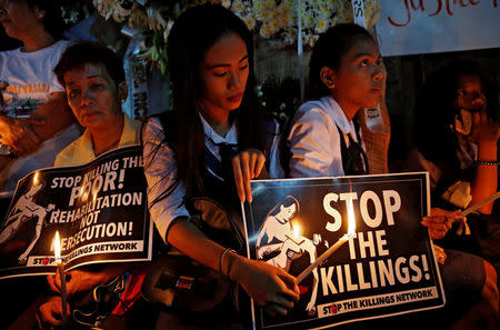 Protesters and residents hold lighted candles and placards at the wake of Kian Loyd delos Santos, a 17-year-old high school student, who was among the people shot dead last week in an escalation of President Rodrigo Duterte's war on drugs in Caloocan city, Metro Manila, Philippines August 25, 2017. REUTERS/Dondi Tawatao/Files