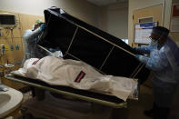Los trabajadores Miguel Lopez y Noe Meza preparan el cuerpo de una víctima del coronavirus para llevarla a la morgue del Providence Holy Cross Medical Center. (Foto: Jae C. Hong / AP).