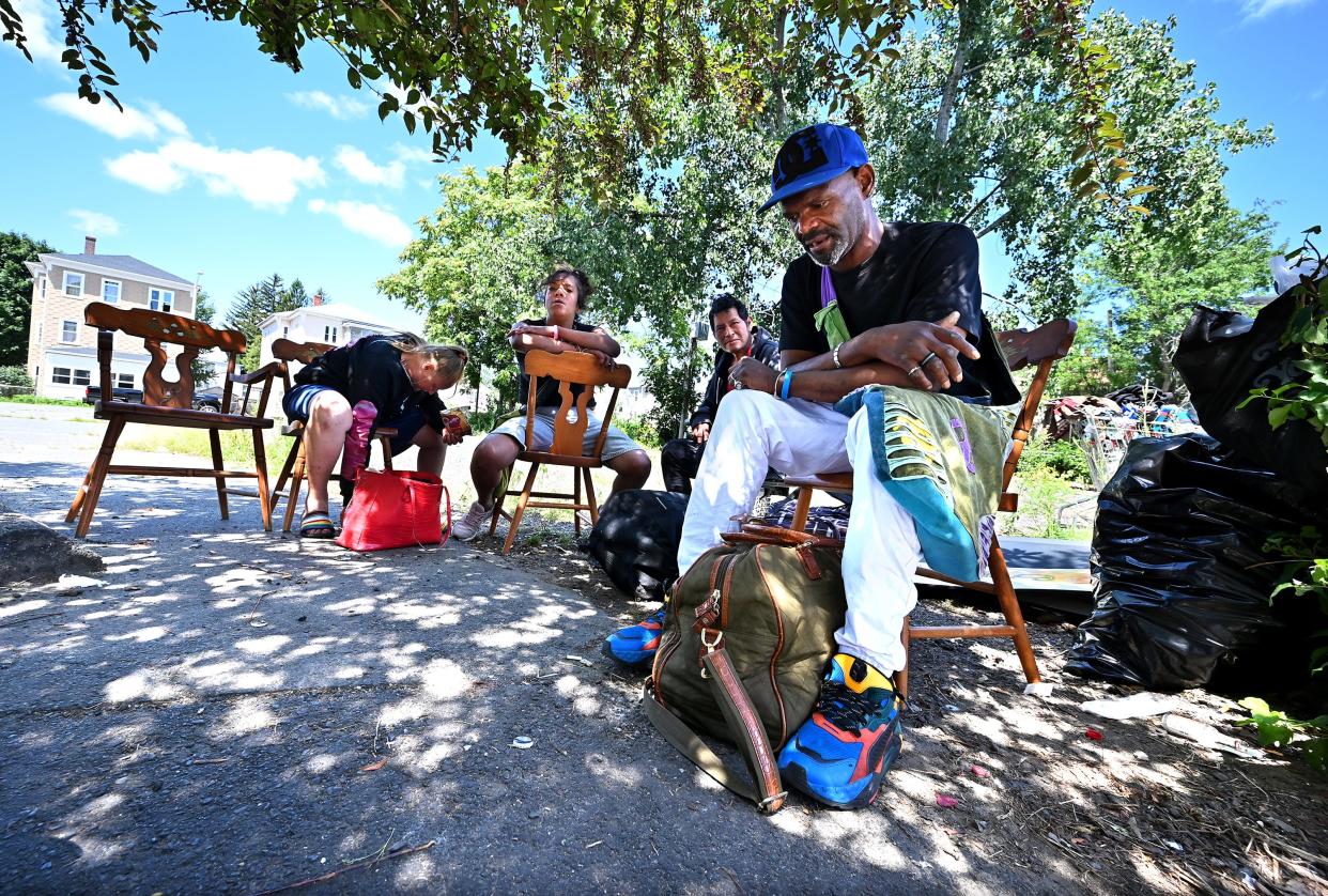 Calvin Gray and several other homeless persons sit in the shade of a crabapple tree in an empty lot on Harding Street.