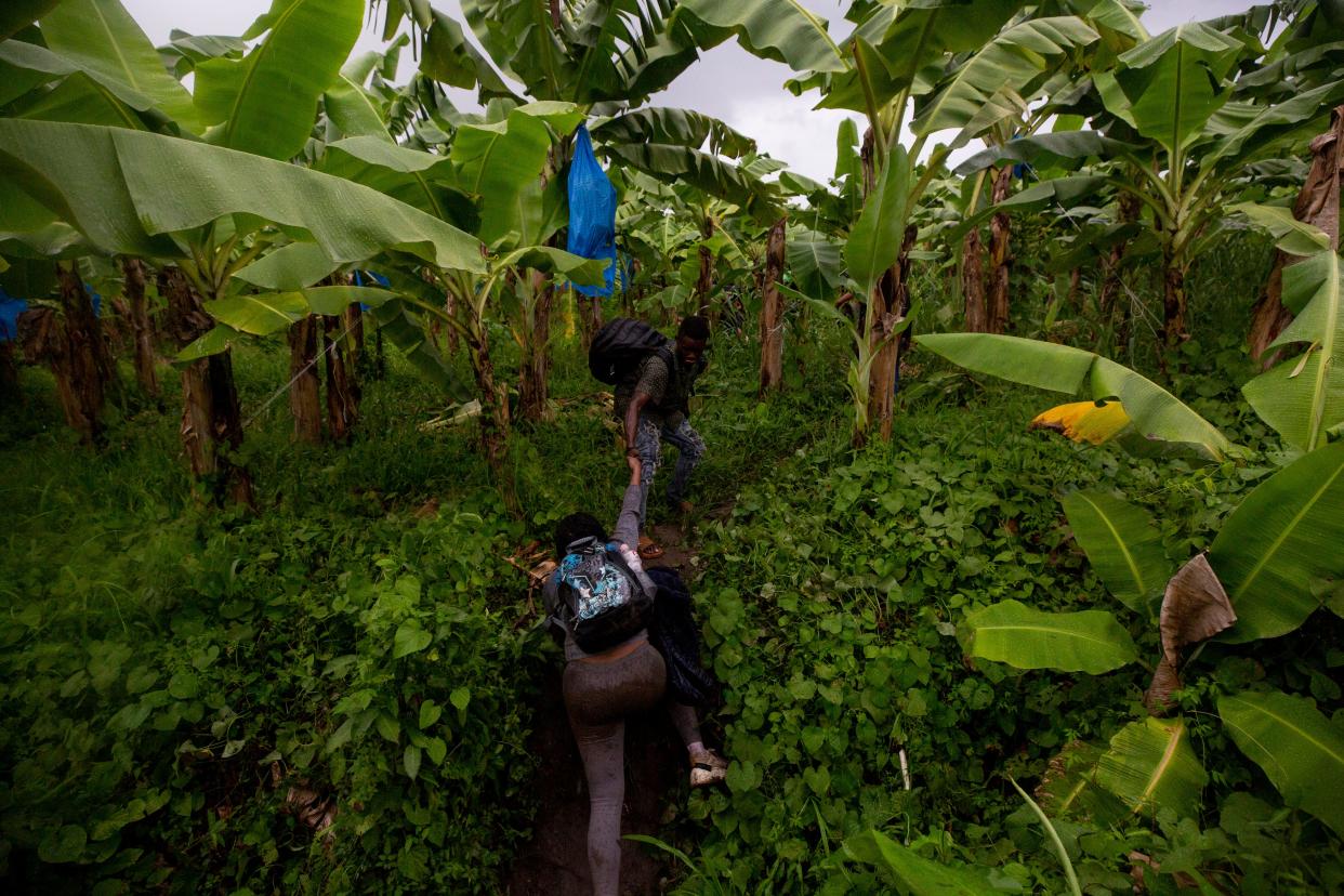 A man helps a fellow migrant climb a ditch in a banana plantation just a few hundred feet from a Mexican immigration checkpoint. The migrants entered the plantation to not be detected by Mexican officials at the first checkpoint on their way to Tapachula from the border between Guatemala and Mexico in October.