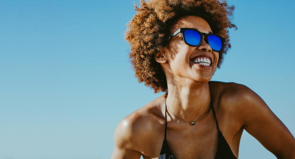 smiling woman outdoors in sun wearing sunglasses