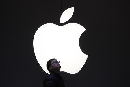 A man stands in front of an Apple logo in downtown Shanghai February 18, 2012. R REUTERS/Aly Song