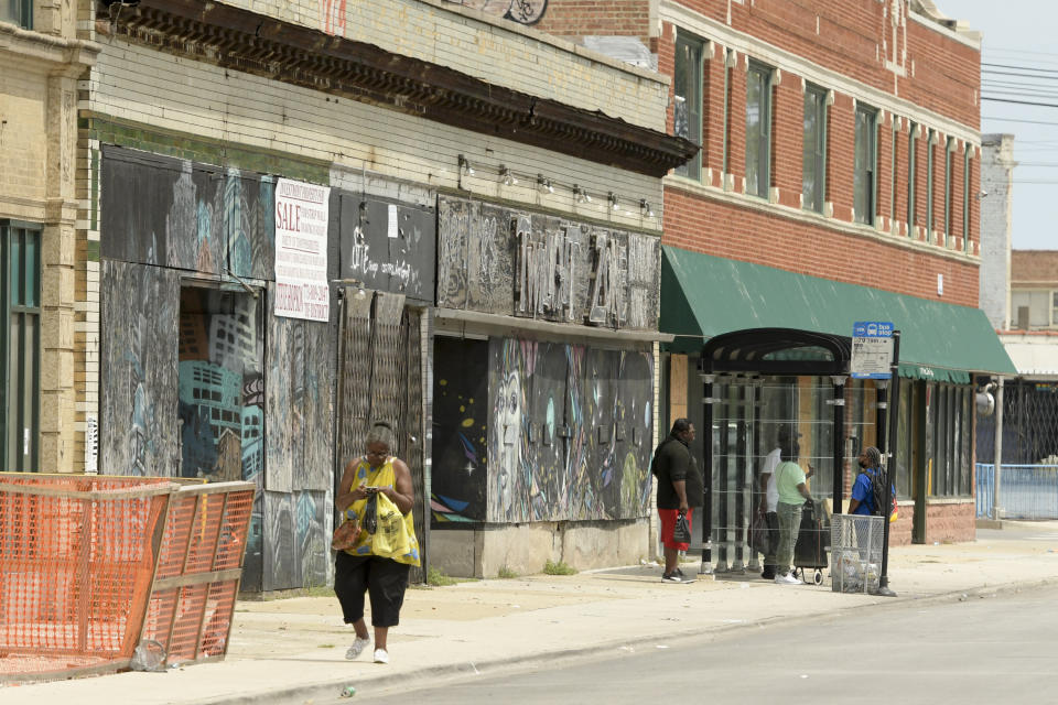 A woman walks past one of the many closed businesses along East 79th Street in Chicago on Friday, Aug. 13, 2021, in a neighborhood on the South Side near where the shooting of Safarian Herring took place in May 2020. (AP Photo/Mark Black)