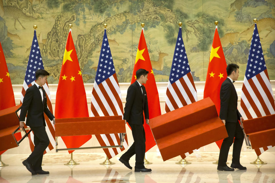 Aides set up platforms before a group photo with members of U.S. and Chinese trade negotiation delegations at the Diaoyutai State Guesthouse in Beijing, Friday, Feb. 15, 2019. (AP Photo/Mark Schiefelbein, Pool)