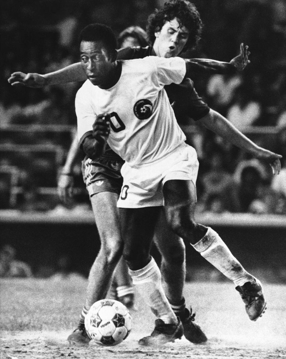 New York Cosmos forward Pelé controls the ball as Miami Toros midfielder Tommy Mulroy defends during the second half of an NASL soccer game at New York's Yankee Stadium on Aug. 10, 1976. Pelé, the Brazilian king of soccer who won a record three World Cups and became one of the most commanding sports figures of the last century, died Thursday, Dec. 29, 2022. He was 82. (AP Photo/Richard Drew, File)