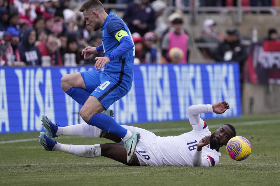 United States defender Shaq Moore (18) is tripped up as he and Slovenia midfielder Timi Max Elsnik battle for the ball during the first half of an international friendly soccer match in San Antonio, Saturday, Jan. 20, 2024. (AP Photo/Eric Gay)