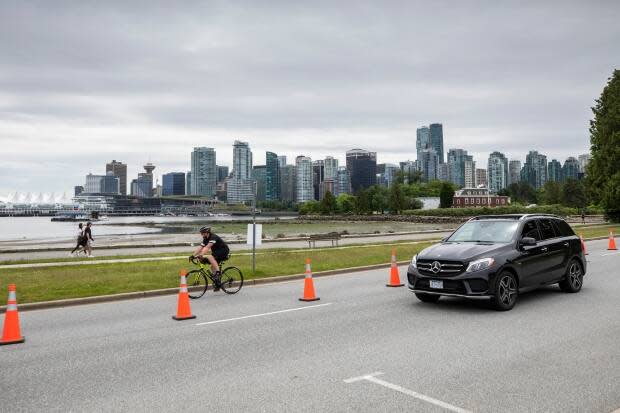 A cyclist and motorist cruise along Stanley Park Drive on June 22, 2020. (Ben Nelms/CBC - image credit)