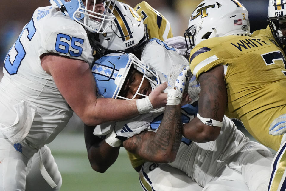 North Carolina running back Omarion Hampton (28) is stopped by Georgia Tech's Trenilyas Tatum (7) and Omar Daniels (21) during the second half of an NCAA college football game, Saturday, Oct. 28, 2023, in Atlanta. (AP Photo/John Bzemore)