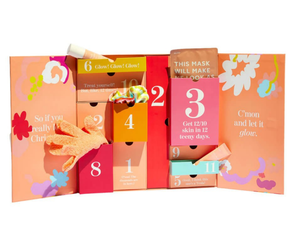 Go-To's peach coloured beauty advent calendar standing upright with its doors open revealing products hanging out, infront of a white background.