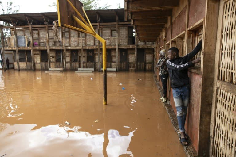Des habitants du bidonville de Mathare s'accrochent aux murs pour traverser une cour d'école inondée, à Nairobi le 24 avril 2024 (SIMON MAINA)