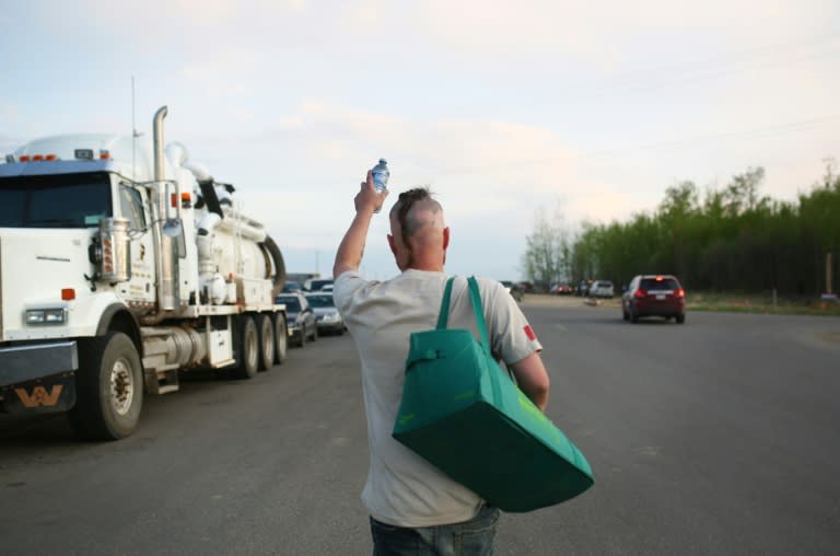 Les Wiley of Cold Lake, Alberta hands out bottles of water to people fleeing their homes threatened by forest fires in Wandering River on May 4, 2016