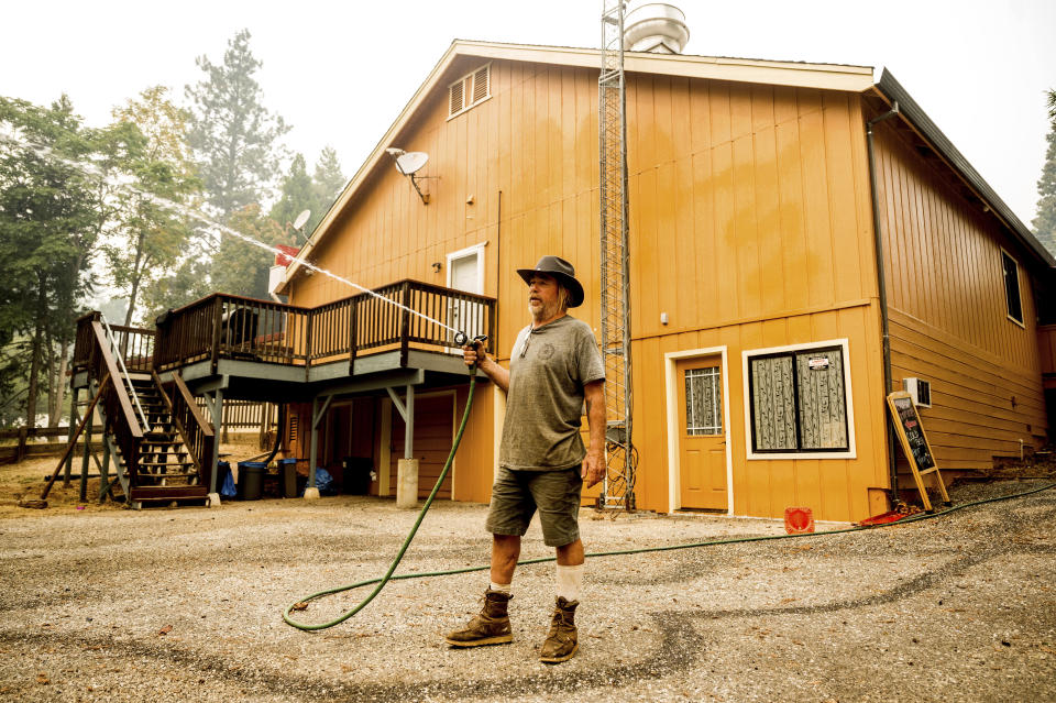 James Lowery sprays water around his friend's restaurant as the Mosquito Fire threatens Foresthill in Placer County, Calif., on Friday, Sept. 9, 2022. (AP Photo/Noah Berger)