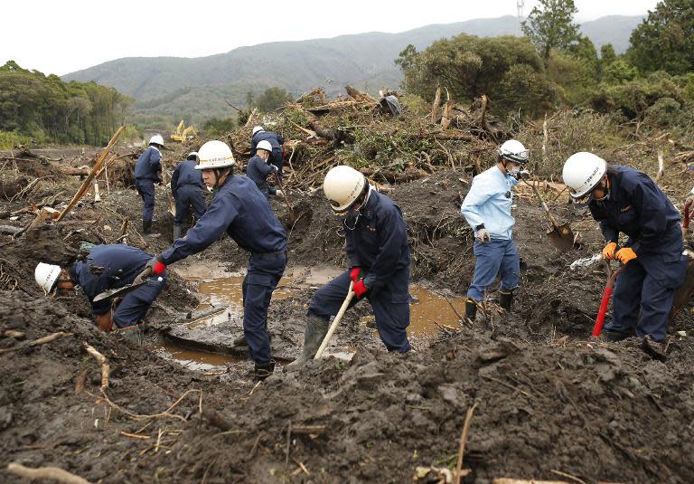 Fire brigade members search for missing people on October 21, 2013 after a landslide caused by heavy rains from Typhoon Wipha hit Oshima island