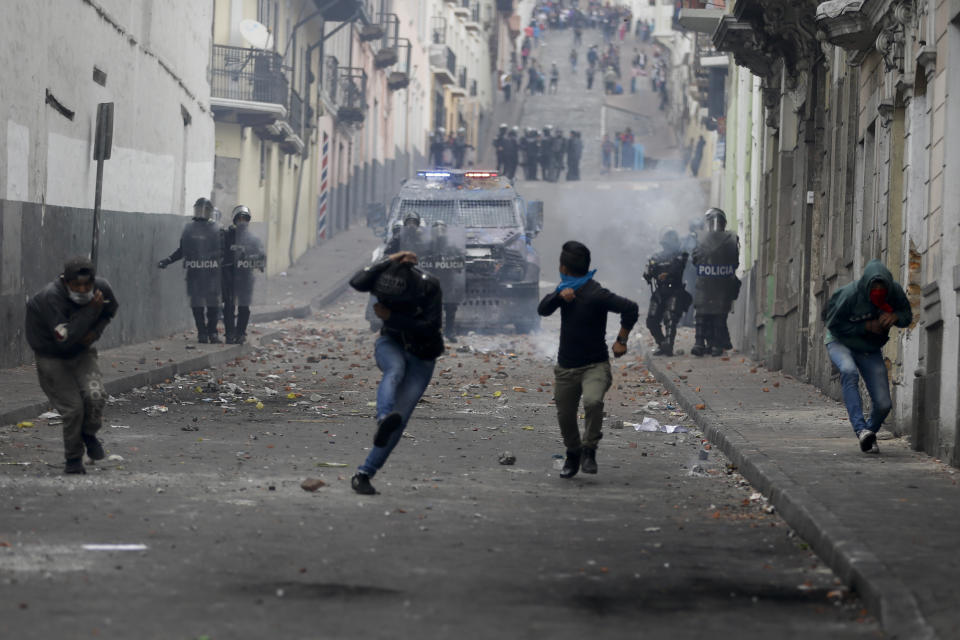 Protesters run from an oncoming armored vehicle and riot police during clashes in downtown Quito, Ecuador, Oct. 8, 2019. (Photo: Fernando Vergara/AP)