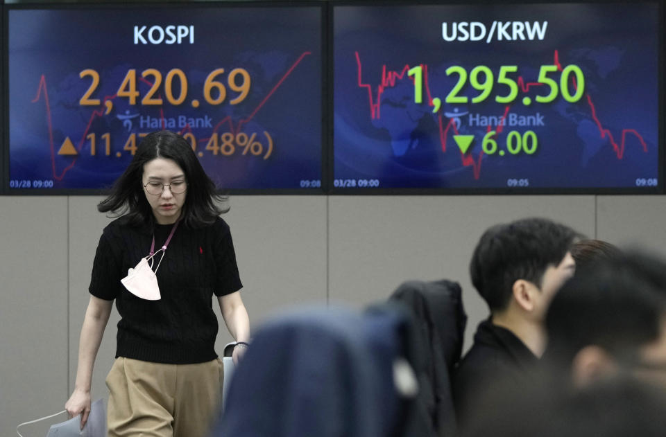 A currency trader passes by the screens showing the Korea Composite Stock Price Index (KOSPI), left, and the foreign exchange rate between U.S. dollar and South Korean won at the foreign exchange dealing room of the KEB Hana Bank headquarters in Seoul, South Korea, Tuesday, March 28, 2023. Asian shares were mostly higher on Tuesday as investors got some relief from worries over troubled U.S. banks with a planned takeover of failed Silicon Valley Bank.(AP Photo/Ahn Young-joon)