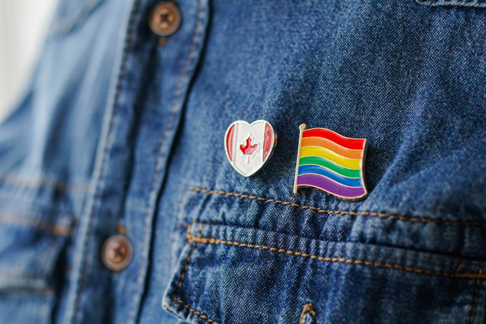 Close up of LGBT pin in the form of a flag with Canada pin is pinned on blue jeans jacket. LGBT rights in Canada concept.