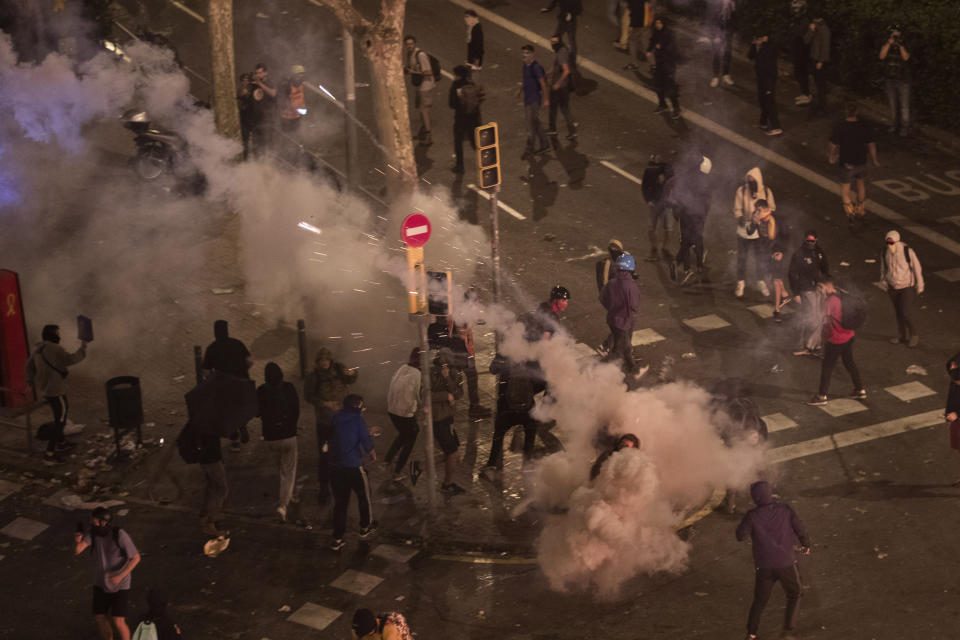Protesters run away from teargas thrown by national police officers, during clashes in Barcelona, Spain, Friday, Oct. 18, 2019.The Catalan regional capital is bracing for a fifth day of protests over the conviction of a dozen Catalan independence leaders. Five marches of tens of thousands from inland towns are converging in Barcelona's center for a mass protest. (AP Photo/Emilio Morenatti)
