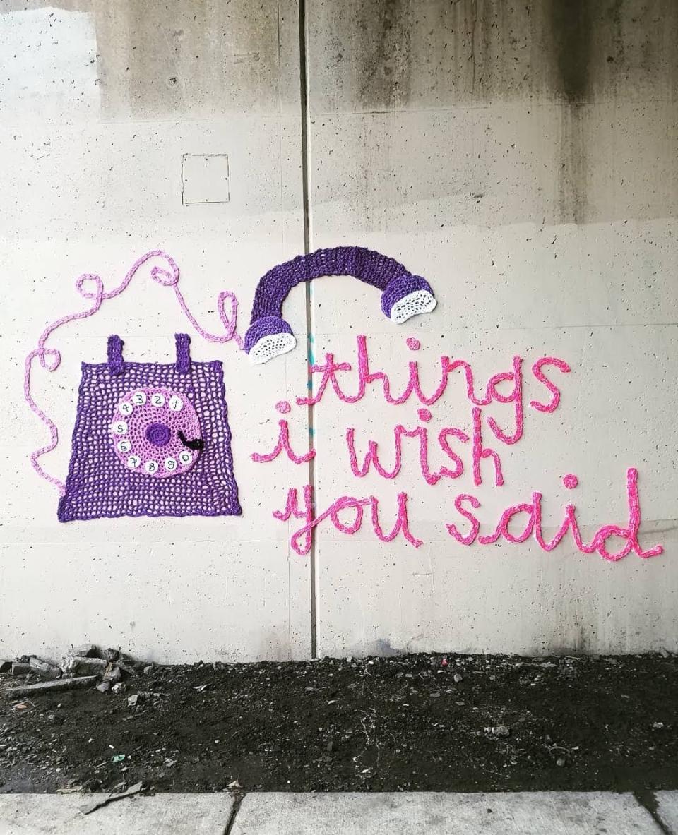 This November 2018 photo provided by Nicole Nikolich shows yarn art pasted under a viaduct in Philadelphia, Pa., which depicts a rotary phone and reads "Things I Wish You Said." Knitters and crocheters call it yarn bombing. They're using fiber arts to make political statements, or maybe just to lift people's spirits. Experts say yarn bombing is part of a long tradition in which women use textile arts to agitate, excite or inspire.(Nicole Nikolich/Lace In The Moon via AP)