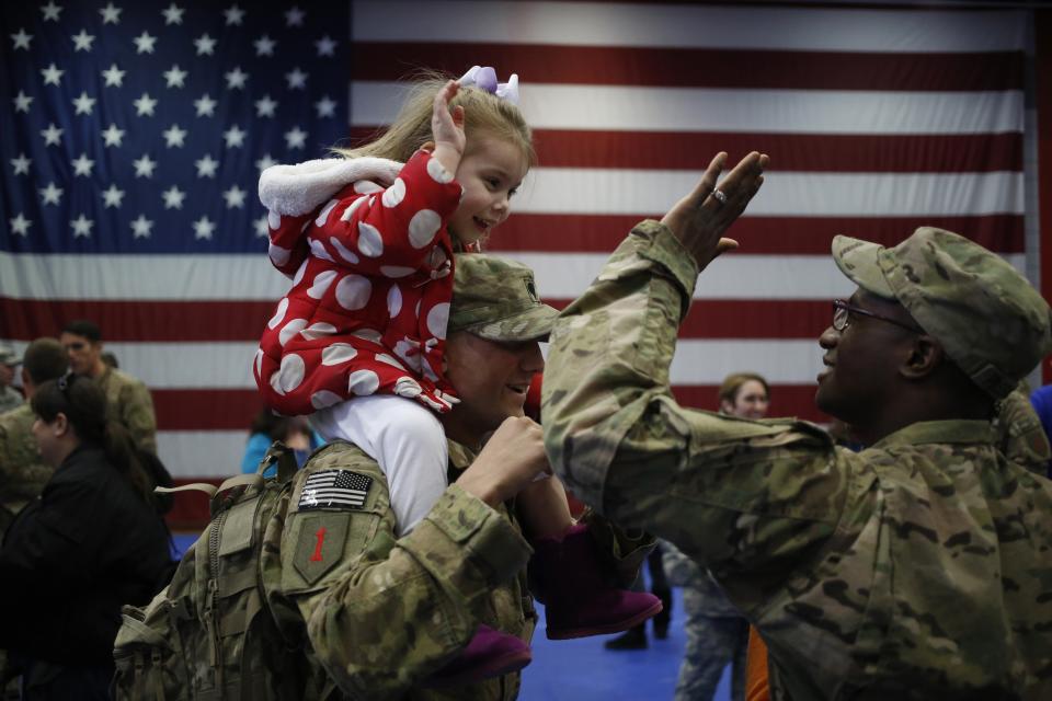 Three-year-old Bella Hanley high fives Sgt. Frank Passmore while sitting atop her dad Spc. Jeffrey Hanley of the U.S. Army's 3rd Brigade Combat Team, 1st Infantry Division, following a homecoming ceremony in the Natcher Physical Fitness Center on Feb. 27, 2014, in Fort Knox, Kentucky.