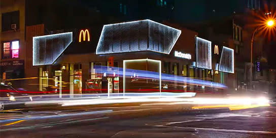 A neon lit McDonald's on the corner of an intersection